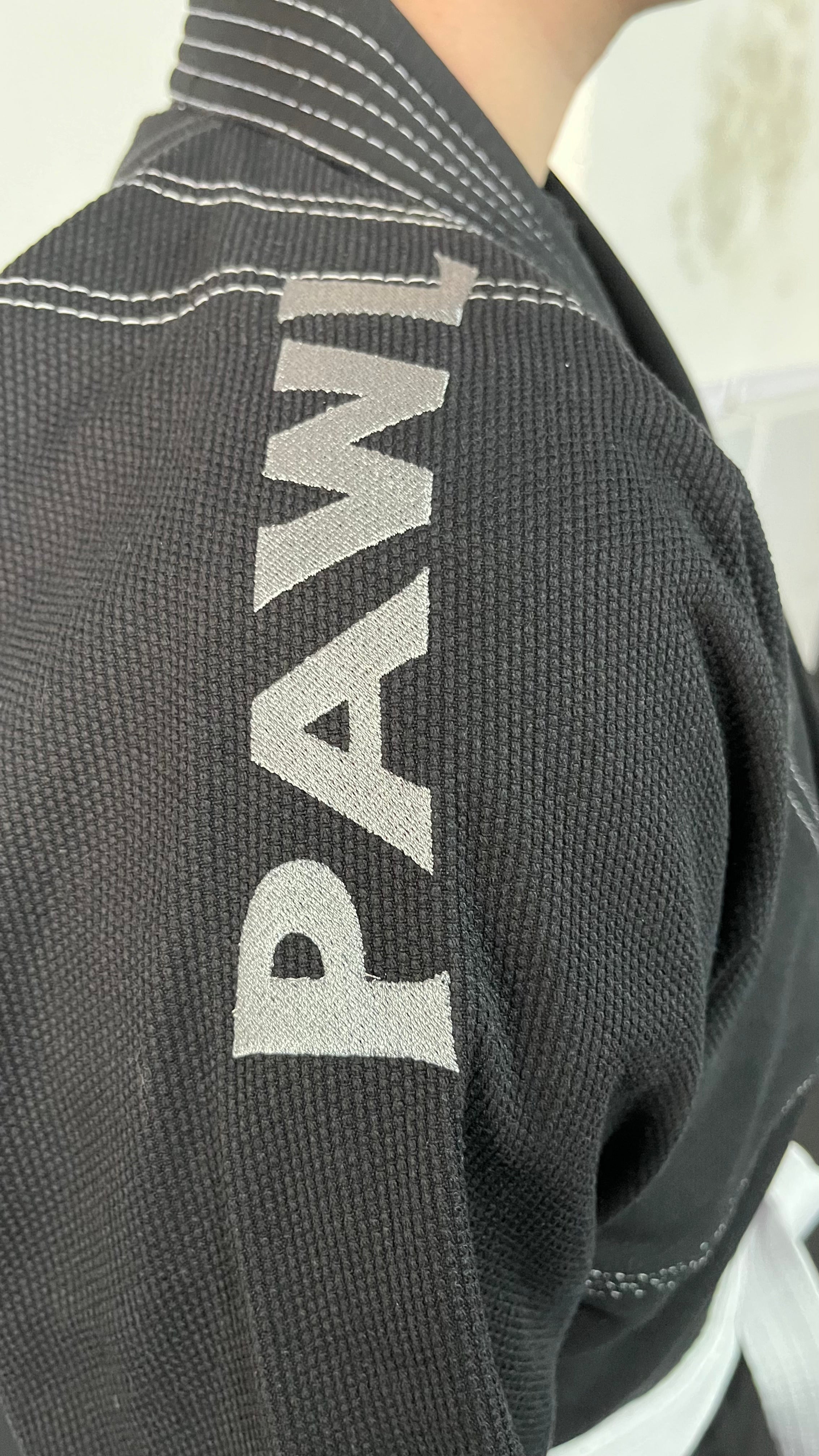 Detalle hombro kimono BJJ negro con logo para entrenamiento